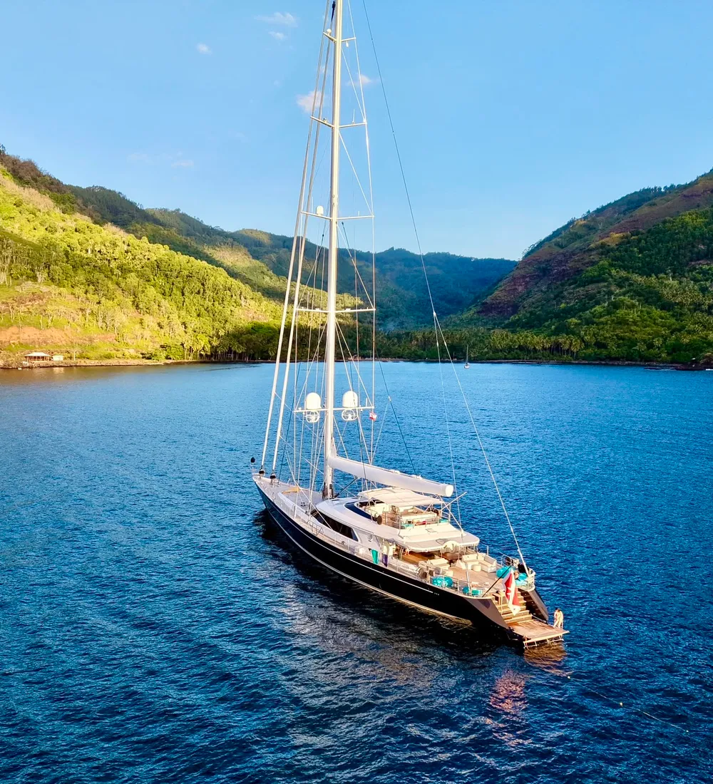 Serendipity I at anchor in a Marquesas bay beneath green volcanic mountains