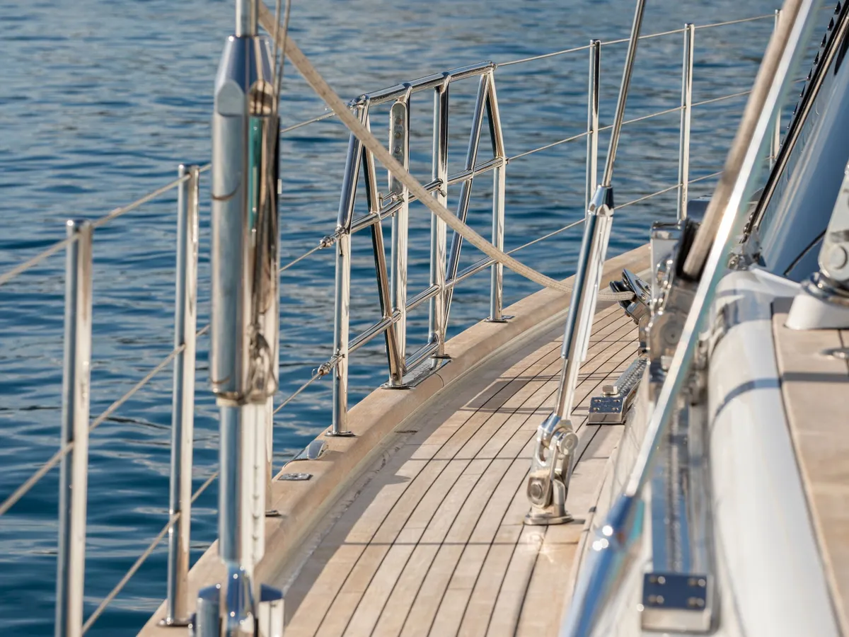 Teak side deck bordered by polished railings and sailing rigging