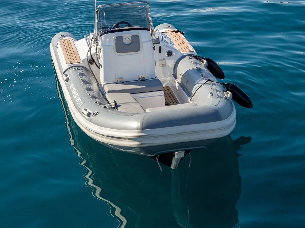 The yacht's RIB tender at anchor on calm blue water, its reflection beneath