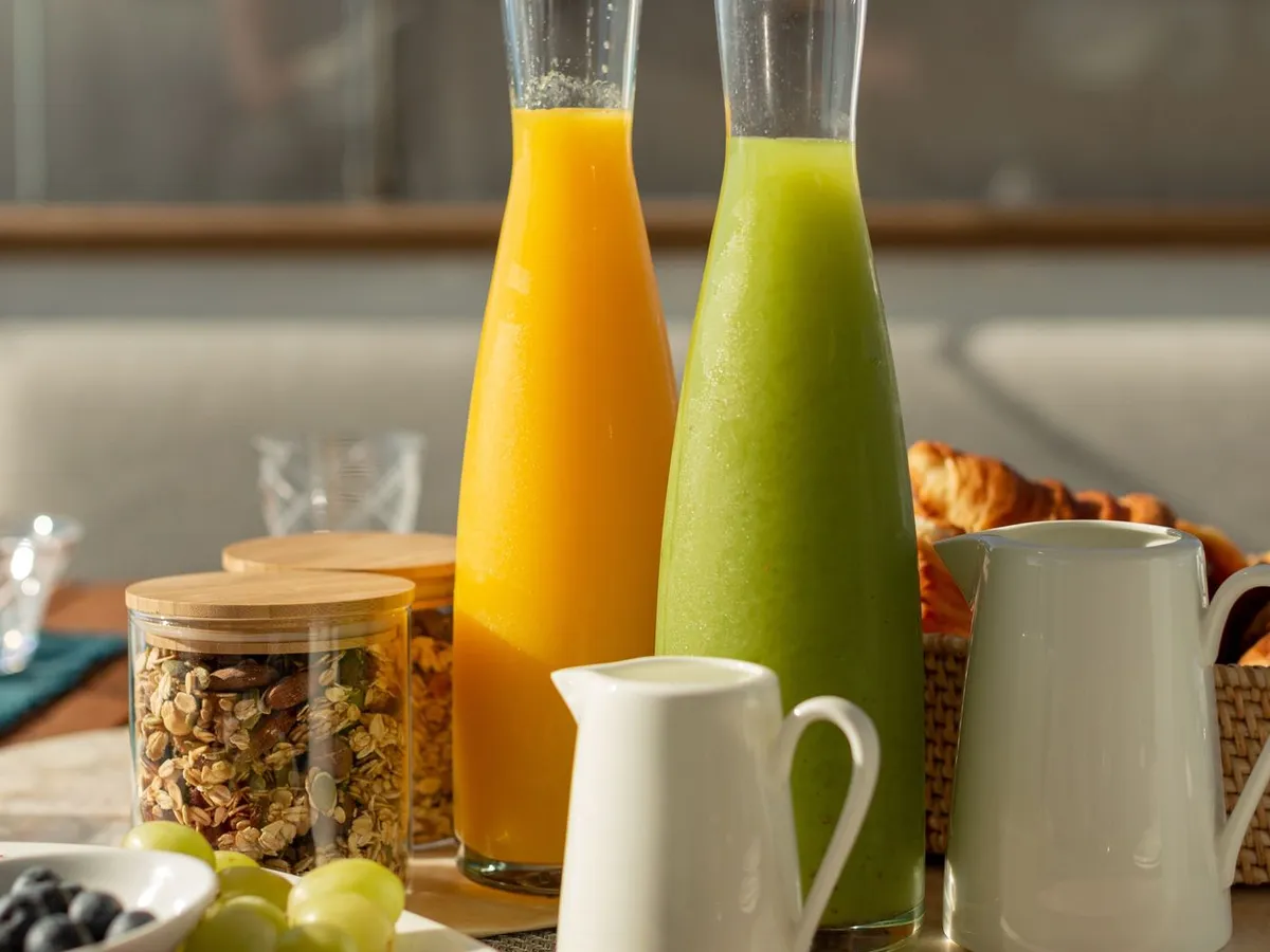 Fresh orange and green juices beside pastries at the breakfast table