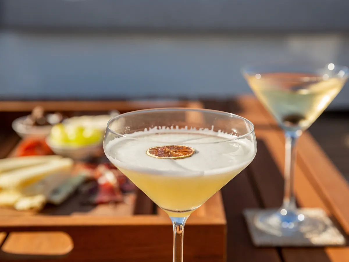 A citrus cocktail and a tray of canapés in the late afternoon light