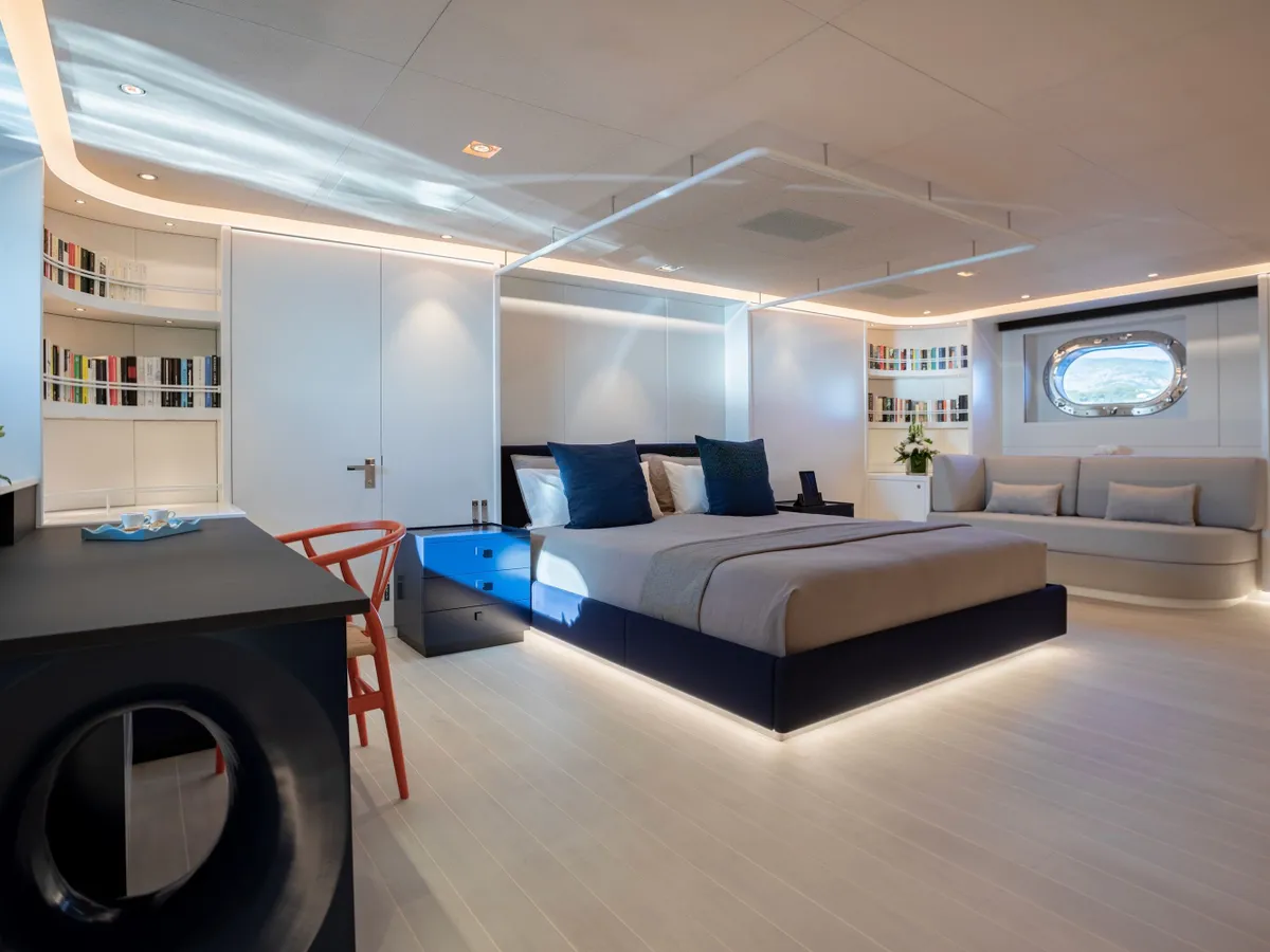 A spacious double cabin with dark blue bed linen and warm concealed lighting