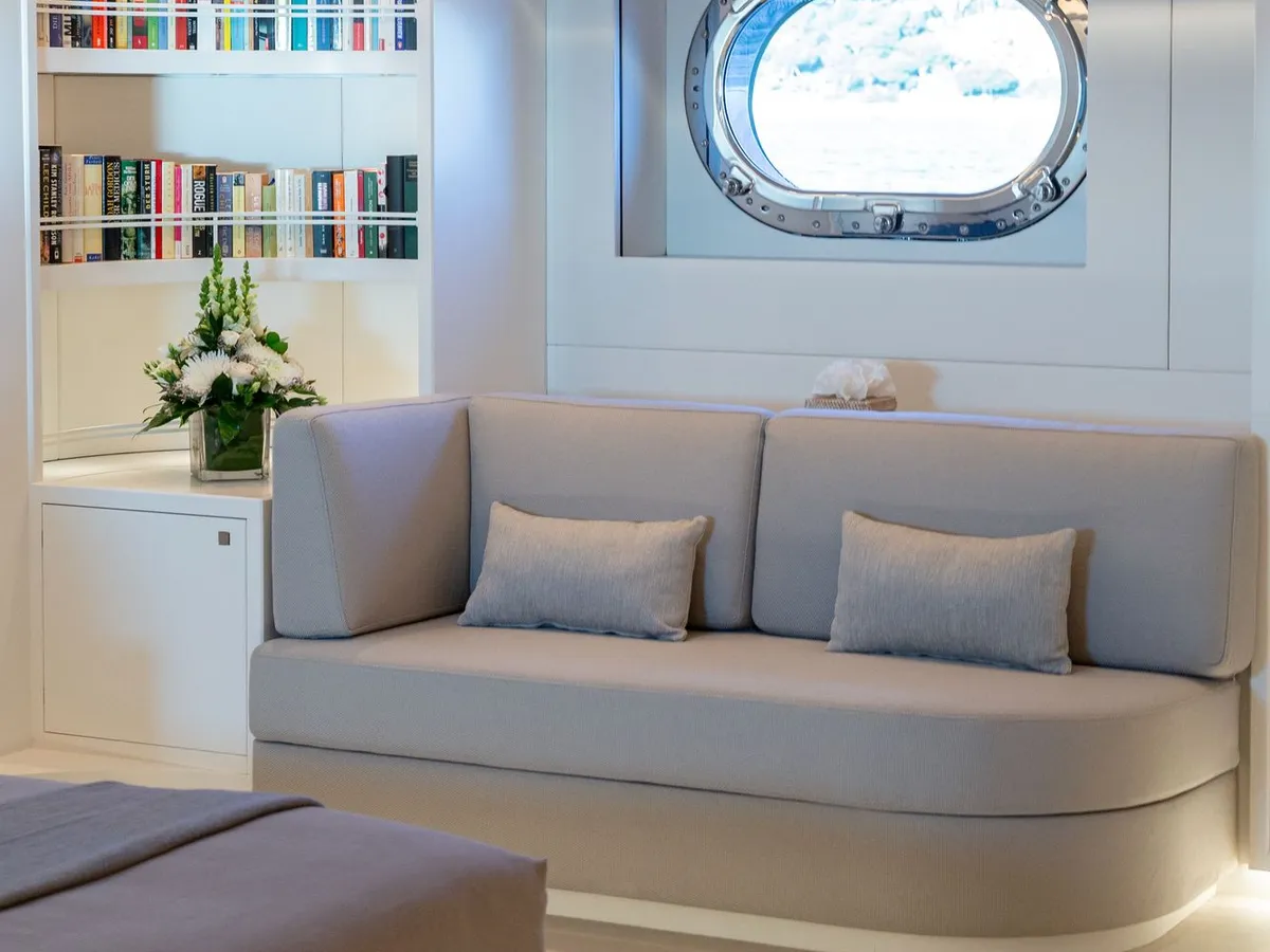 A reading sofa beside a built-in bookcase and a round porthole window
