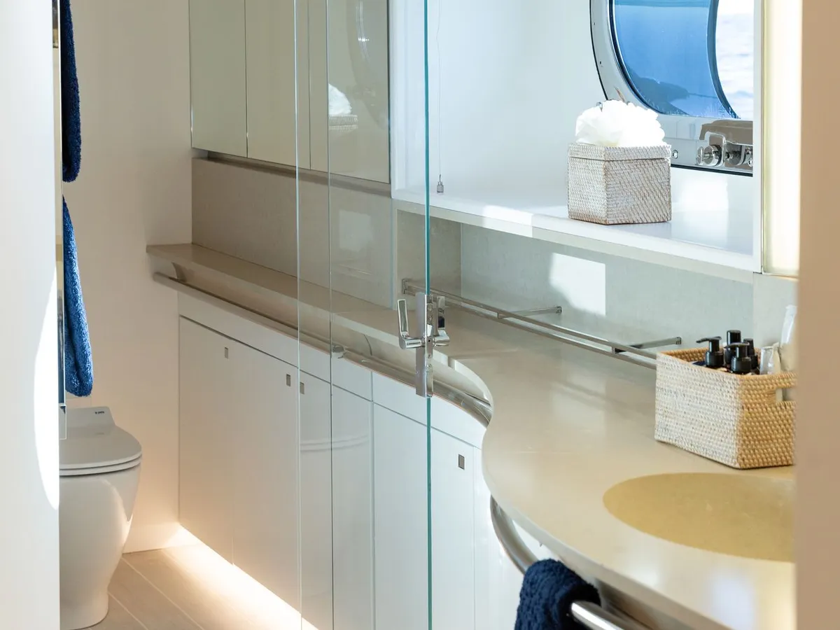 A cabin ensuite with a glass shower enclosure and a round porthole
