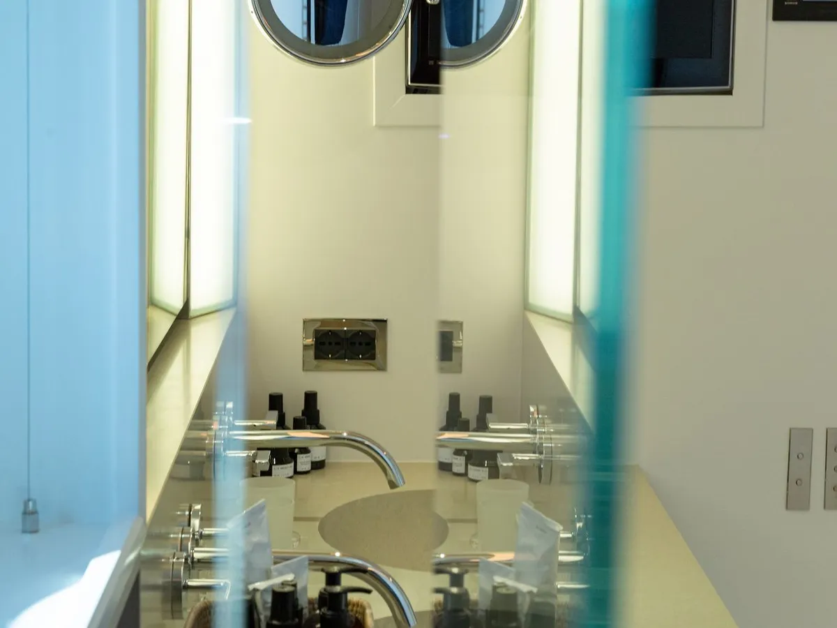 A dual-basin bathroom vanity with a mirrored cabinet and woven amenity baskets