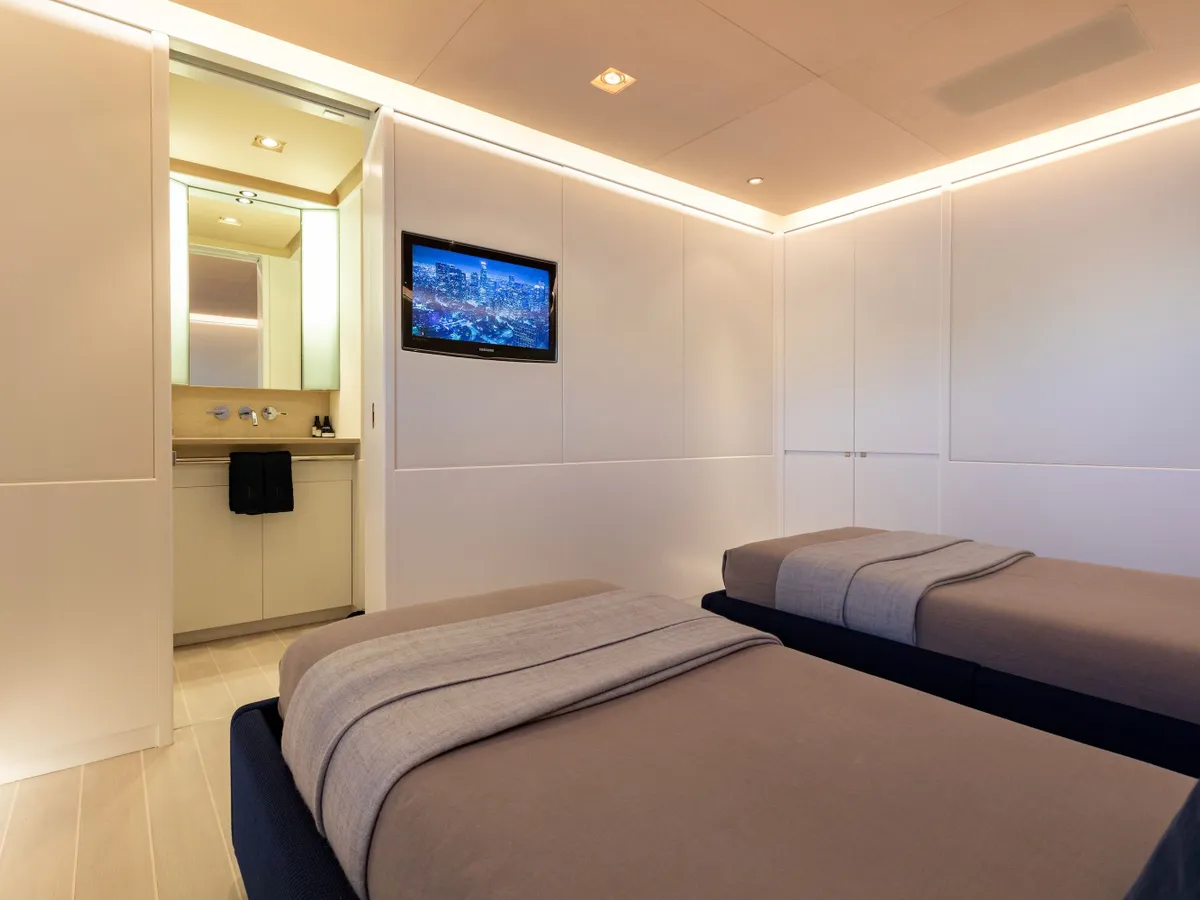 A softly lit twin guest cabin with pale walls and navy bed covers