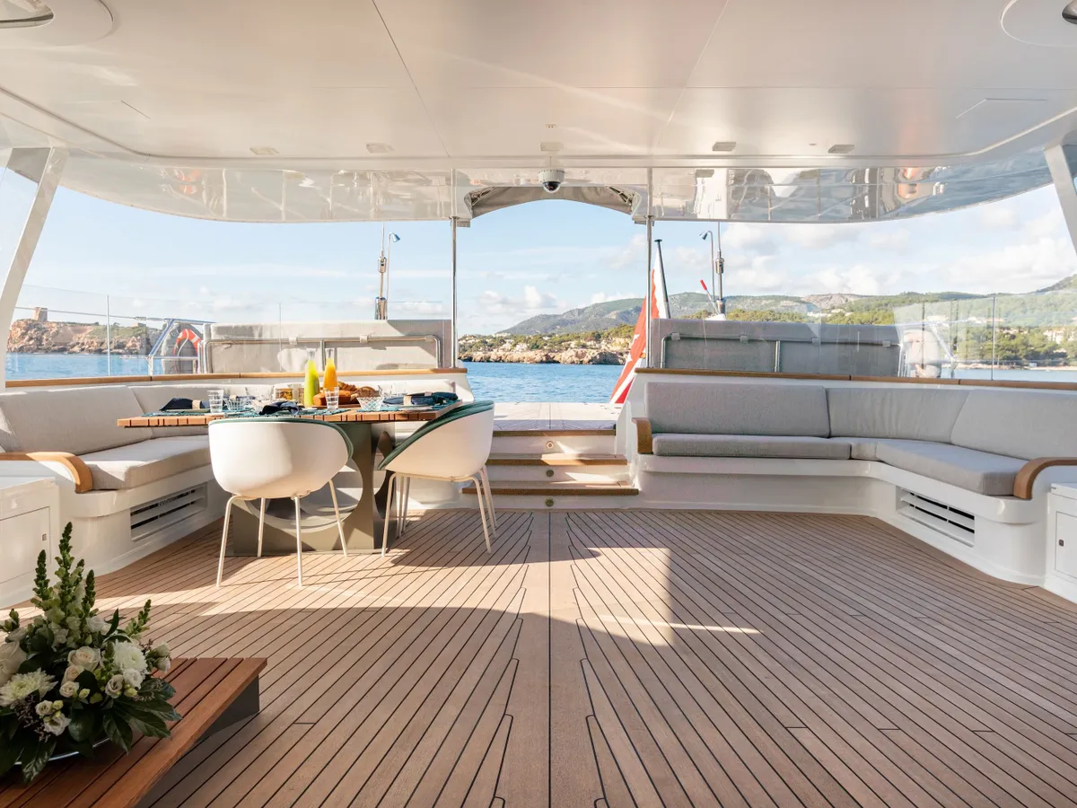Warm sunlight across the teak aft deck and its shaded seating area