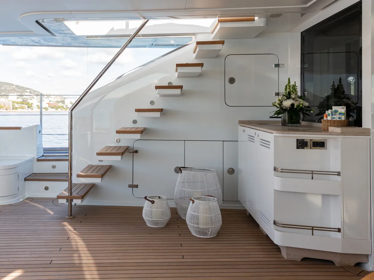Teak-treaded stairs curving from the aft deck to the flybridge, with the galley bar alongside