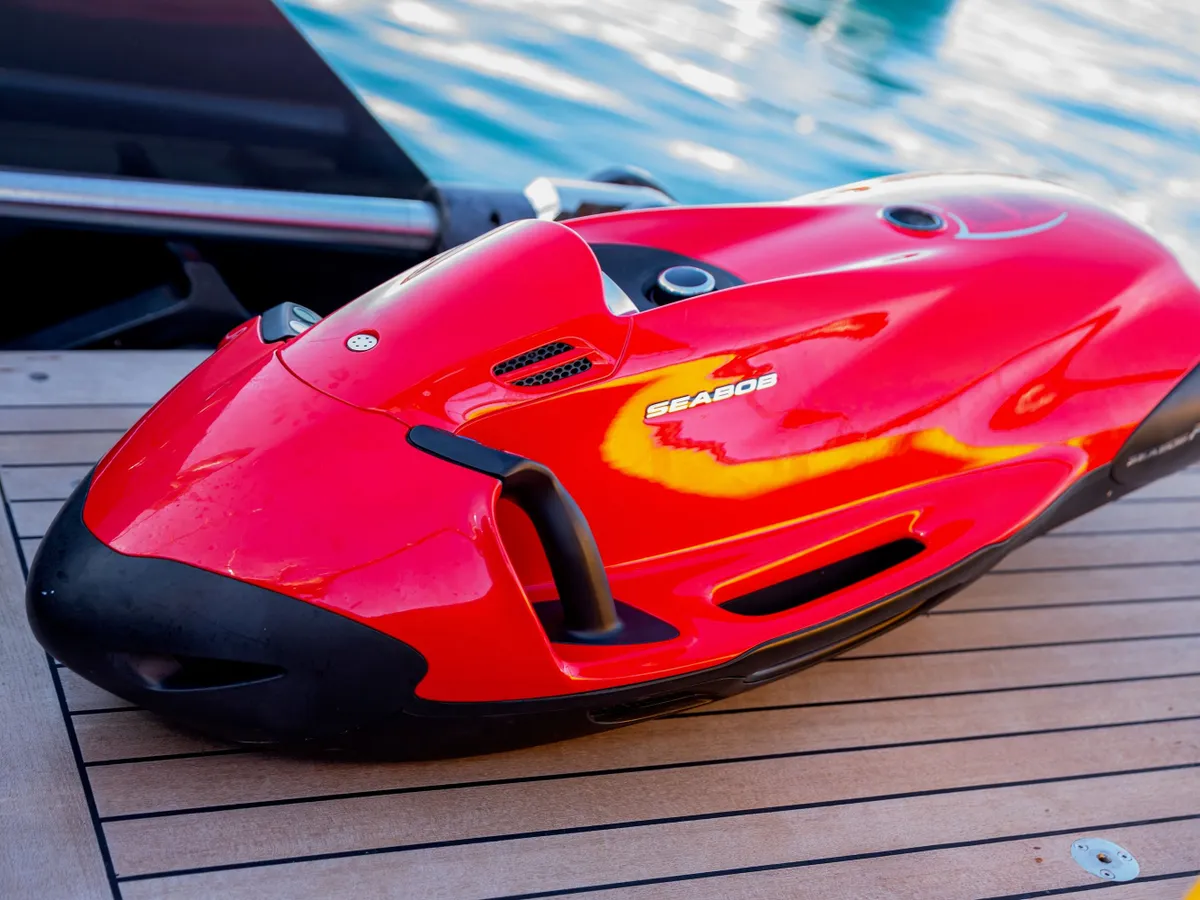 A red Seabob underwater scooter resting on the teak swim platform
