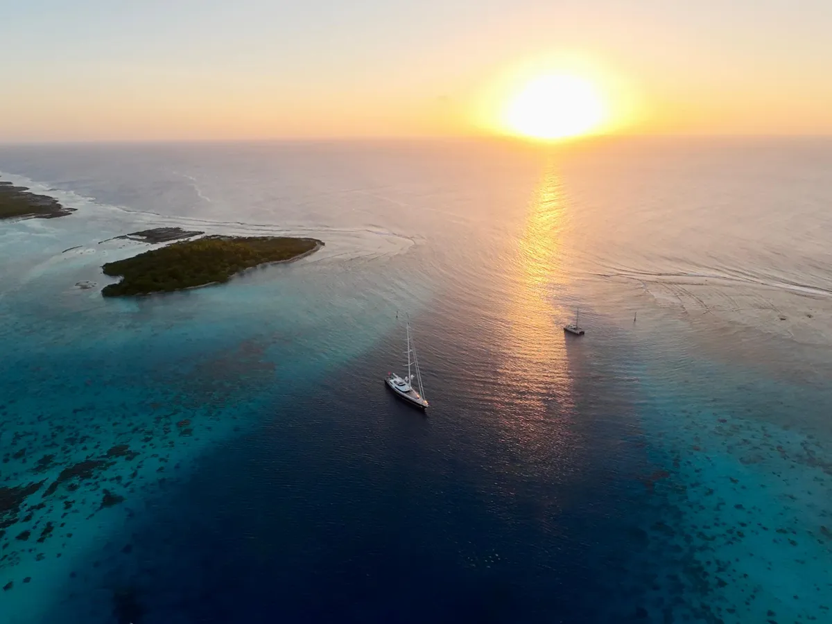 Serendipity I anchored near small reef islets at sunset with another yacht nearby