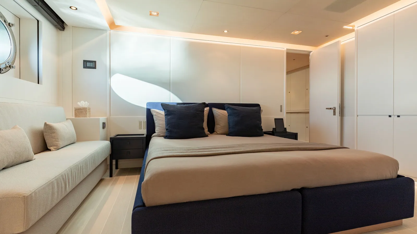 A double guest cabin with navy cushions, white cabinetry and a porthole