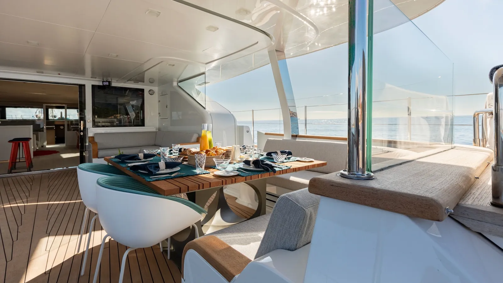The sheltered aft deck with a dining table, white sofas and views across the harbour