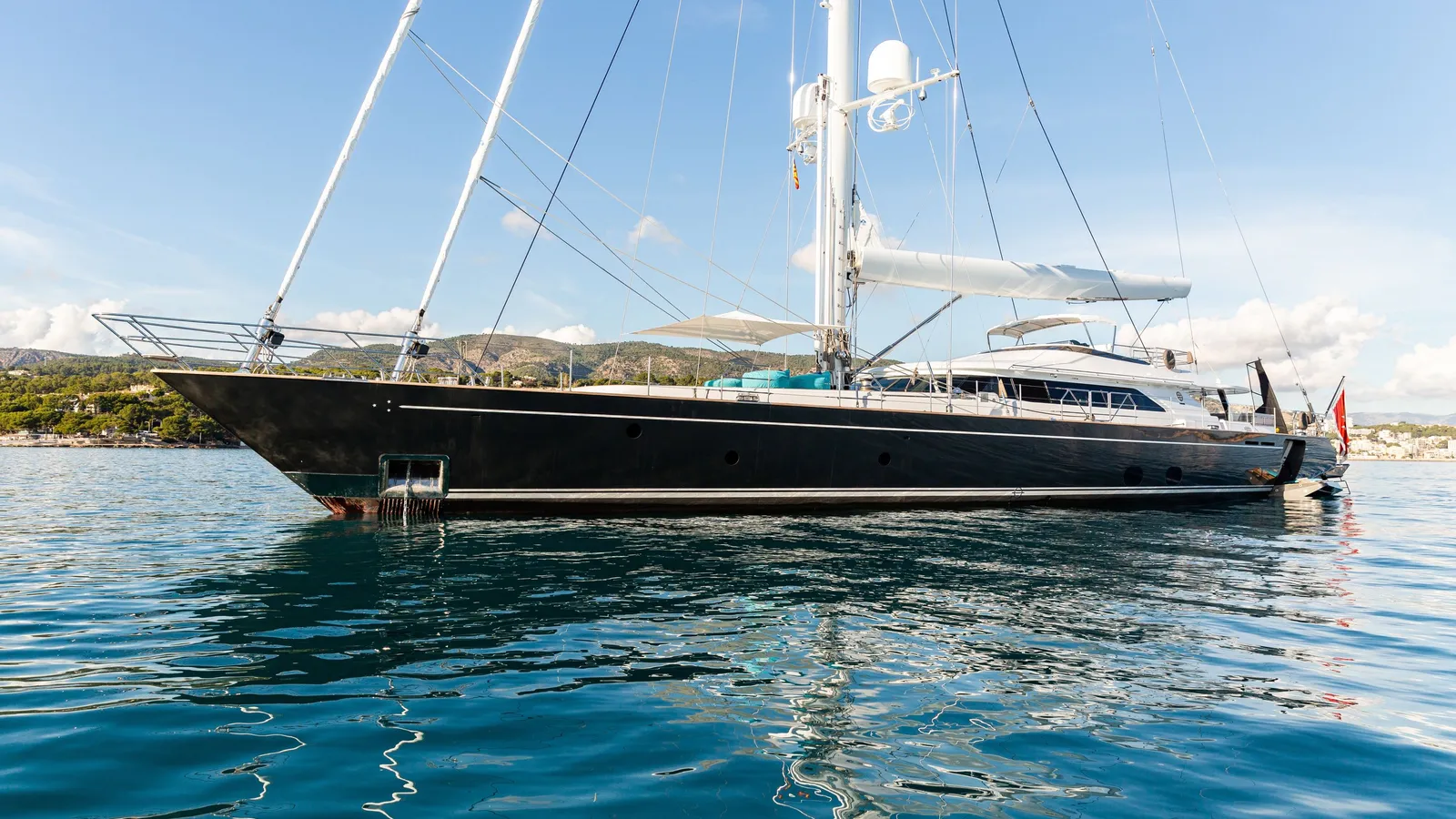 Serendipity I at anchor, her dark hull reflected in clear blue water