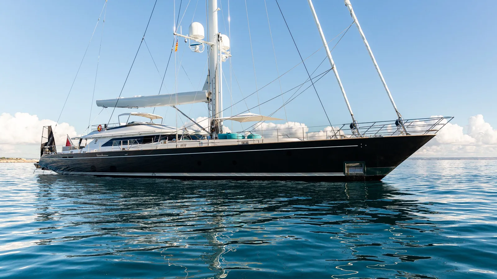 Serendipity I at anchor under bare poles, full side profile against open sea and sky