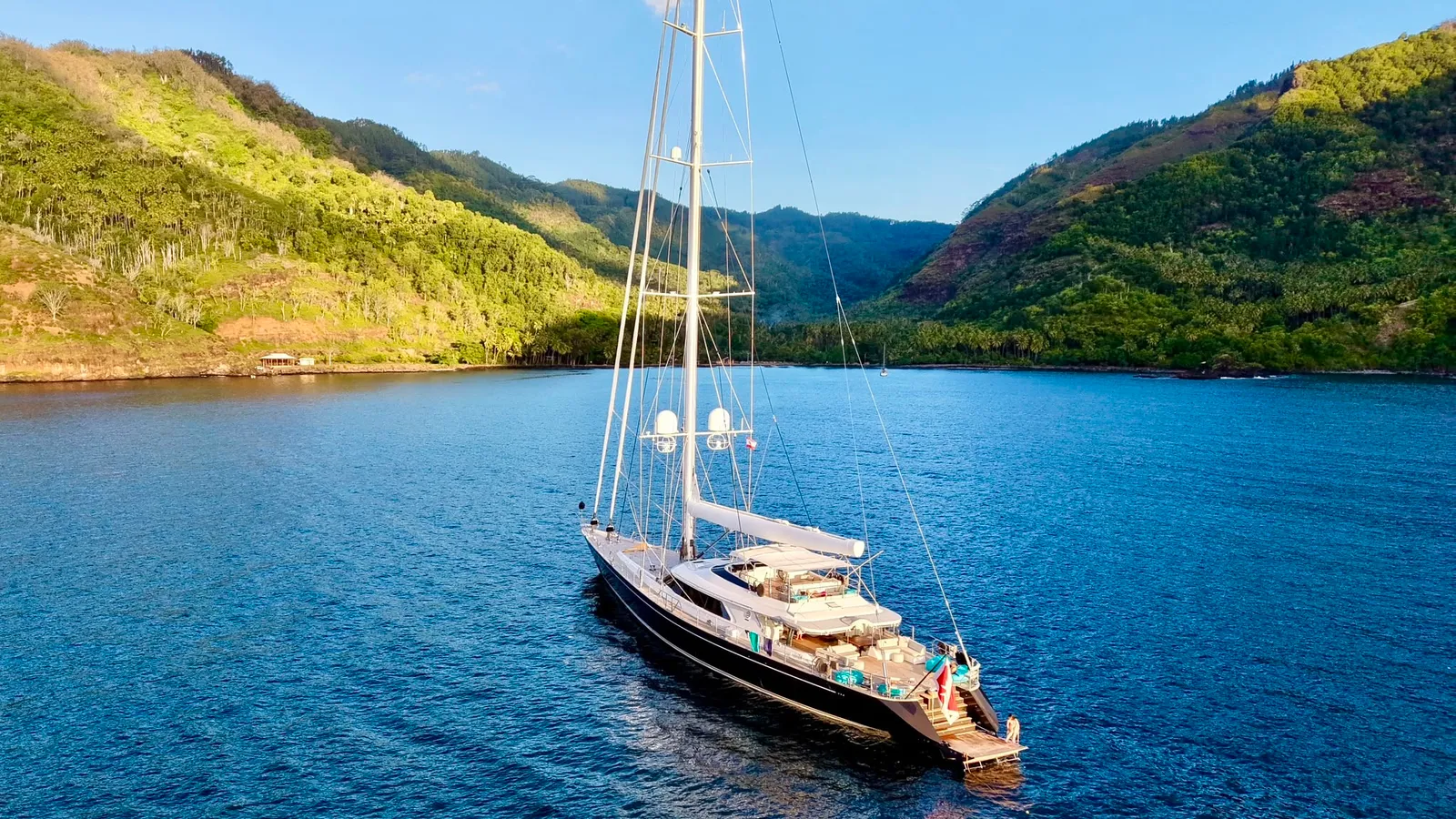 Serendipity I at anchor in a Marquesas bay beneath green volcanic mountains