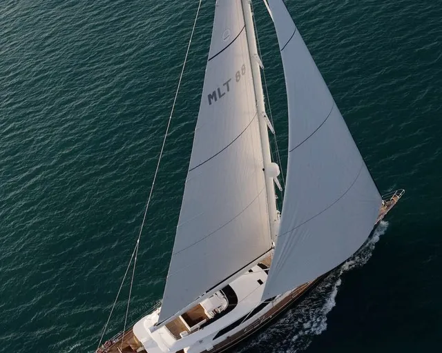 Sailing yacht from above with both sails deployed on calm blue water