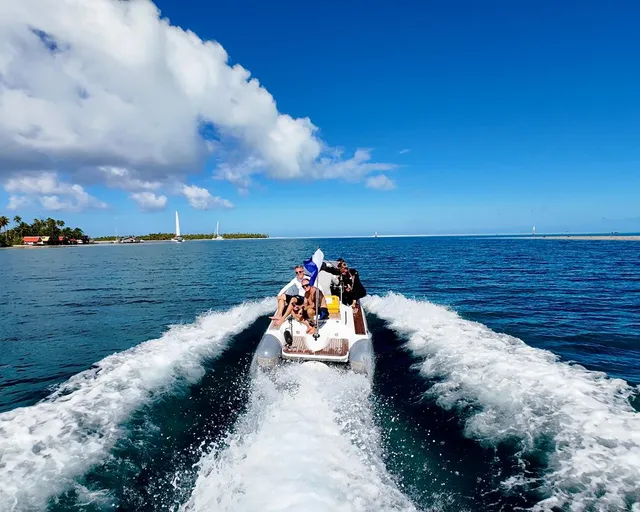 Speedboat with passengers departing from island with wake spray