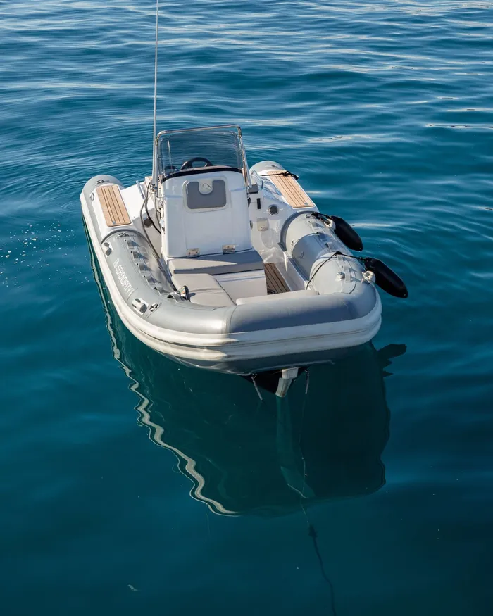 The RIB tender at anchor on calm blue water, seen from above