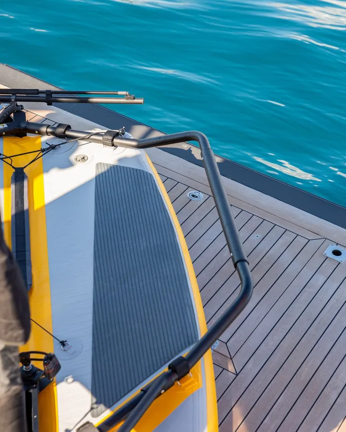 A SUP board strapped to the swim step, seen from above against turquoise water